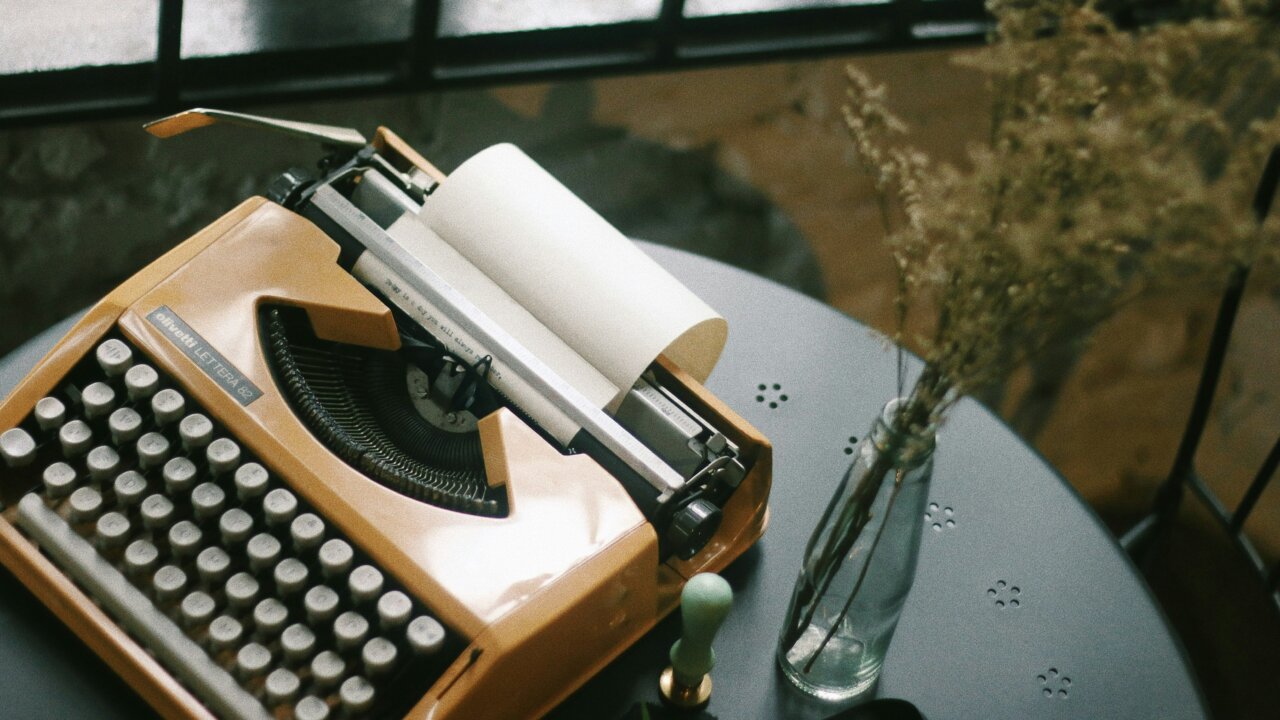 Typewritter on a table. Some words have been started. Light from a window shines in to highlight the scene.