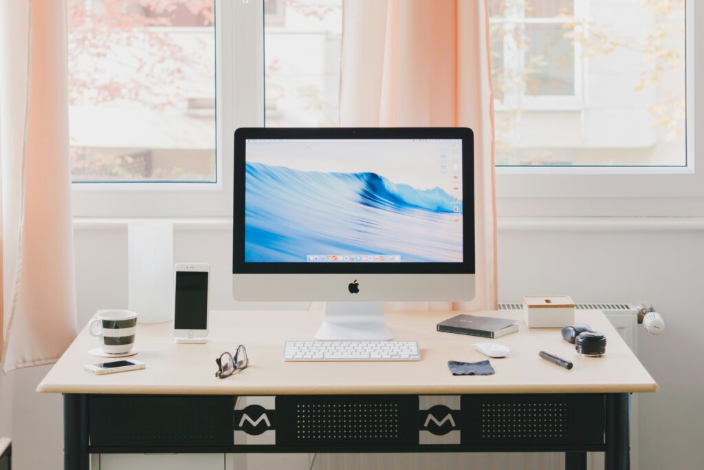 An asthetic desk scene with a older generation imac, iphone and other peripherals neatly laid out.
