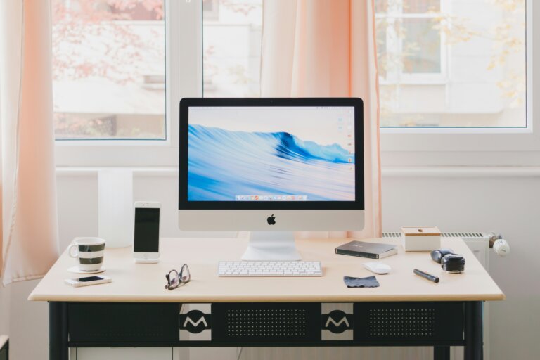 An asthetic desk scene with a older generation imac, iphone and other peripherals neatly laid out.
